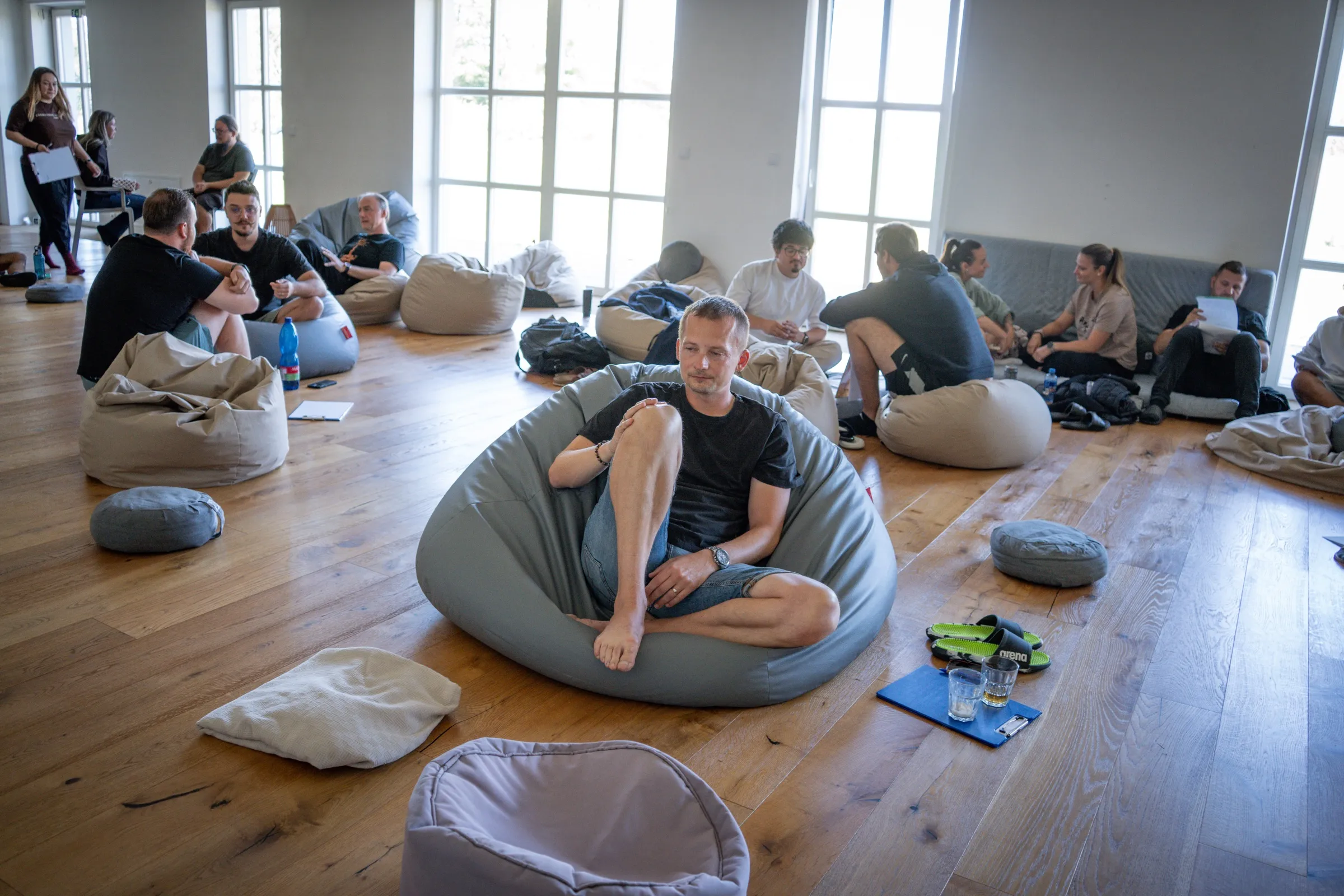 Workshop týmu (ant): lidé na sedacích vacích ve světlé místnosti.